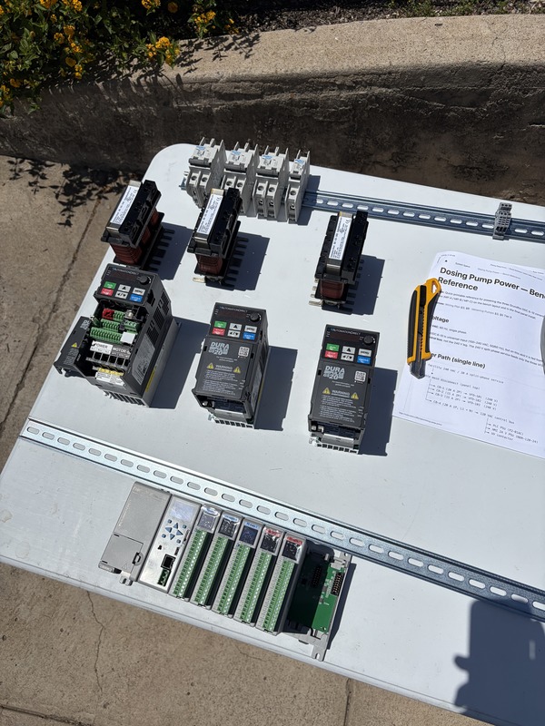 Laying out the first AutomationDirect components for the PLC like the line reactors, VFDs, and circuit breakers along with DIN rail on a folding table to prep